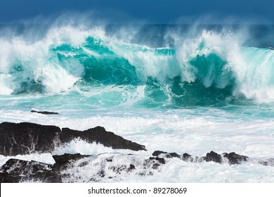 Turquoise rolling wave slamming on the rocks of the coastline - Powered by Shutterstock