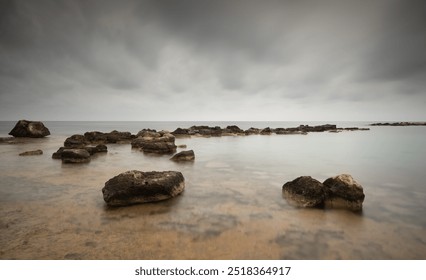 Turquoise sea water gently washing over rocks on the coast on a cloudy day. Cape Greko peninsula Cyprus - Powered by Shutterstock