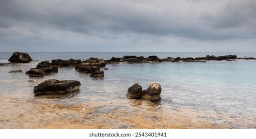 Turquoise sea water gently washing over rocks on the coast on a cloudy day. Cape Greko peninsula Cyprus - Powered by Shutterstock