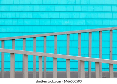 Turquoise shingle wall with grey wooden fence, typical of the arcthiecture of the Magdalen Islands, Canada. Decorative minimalist background with focus on front rail.