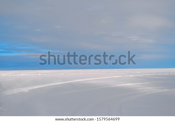 A turquoise sky above
a snow field. The horizon between the sky and the snow field
divides the frame in a ratio of one to three. It is possible to
place text at the top.