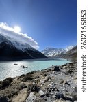 The turquoise waters of Hooker Lake reflect the snow-capped peaks of Aoraki, Mount Cook in New Zealand, under a bright sun, a stunning alpine landscape.