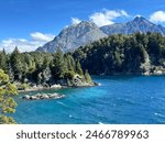 Turquoise waters of the Nahuel Huapi lake in front of the Lopez mountain. With green pines in the center. Villa Tacul, Bariloche , Patagonia, Argentina