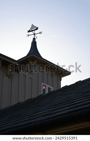 Turret roof and weathervane on roof of old coastguard building in sunset silhouette at South Shields, North East England.