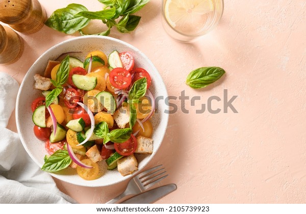 Tuscan Panzanella salad with tomatoes, red onion,\
cucumbers and crispy croutons on pink background. Top view.\
Traditional Italian cuisine. Vegetarian panzanella salad.\
Mediterranean healthy\
food.