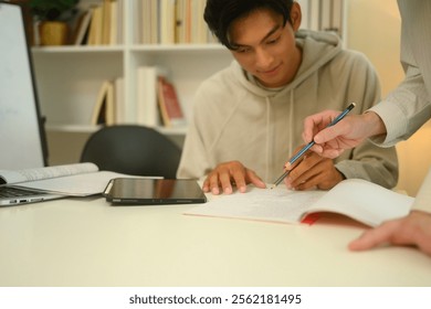 Tutor pointing to important sections in a notebook assisting a student during a study session