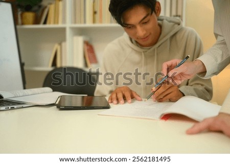 Tutor pointing to important sections in a notebook assisting a student during a study session