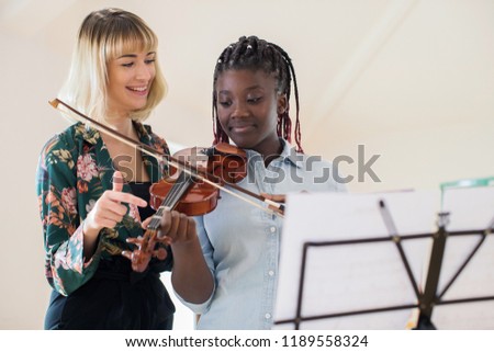 Tutor Teaching High School Student To Play Violin In Music Lesson