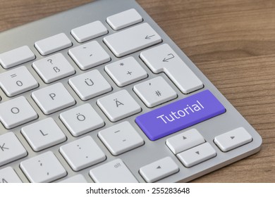 Tutorial written on a large blue button of a modern keyboard on a wooden desktop