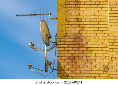 TV aerial and satellite parabolic antennas attached to the wall of the house.