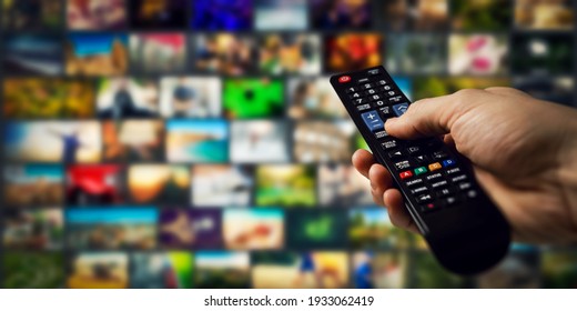tv channels in background and remote control in hand. smart television and content on demand concept