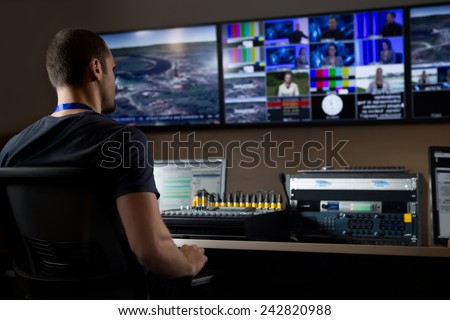 TV engineer at editor in studio. TV editor working with vision mixer in a television broadcast gallery.Man sat at a vision mixing panel in a television studio gallery