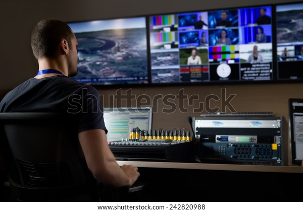 TV engineer at editor in\
studio. TV editor working with vision mixer in a television\
broadcast gallery.Man sat at a vision mixing panel in a television\
studio gallery
