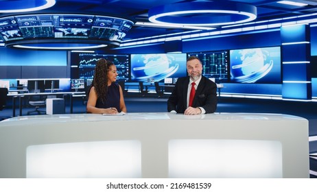 TV Live News Program: Two Professional Presenters Reporting On The Events. Television Cable Channel Newsroom Studio: Male And Female Anchors Talk. Mock-up Broadcasting Network Concept. Wide Shot