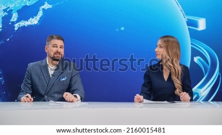 TV Live News Program: Two Presenters Reporting, Discuss Daily Events, Discuss Business, Economy, Science, Entertainment. Television Cable Channel Diverse Anchors Talk. Newsroom Studio Concept