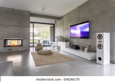 Tv living room with window, fireplace and concrete wall effect - Shutterstock ID 554246170