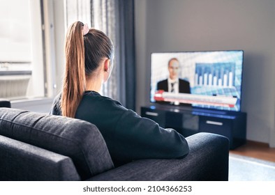 Tv News. Woman Watching Television Broadcast In Home Living Room. Reporter, Anchor And Studio Host In Screen With Newscast Headlines. Person Sitting On Couch. Politics Channel On Election Morning.