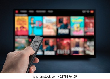 Tv online. Television streaming video. Media TV on demand. Online Multimedia video concept on TV set in dark room. Watching online TV with remote control in hand. - Shutterstock ID 2179196459