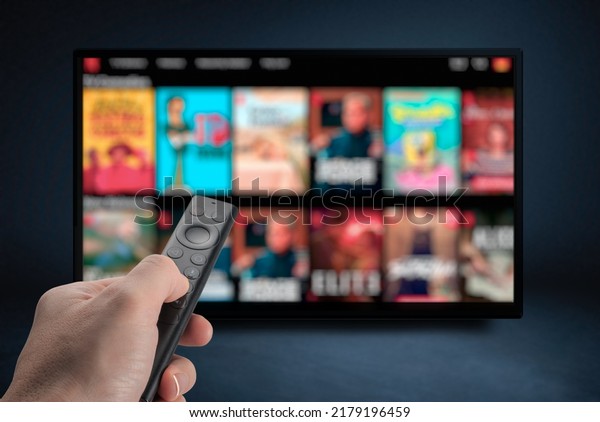 Tv online. Television\
streaming video. Media TV on demand. Online Multimedia video\
concept on TV set in dark room. Watching online TV with remote\
control in hand.