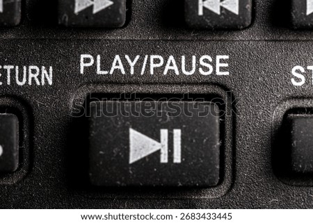 Tv play and pause icon and button close up of a old dusty black Television remote controller