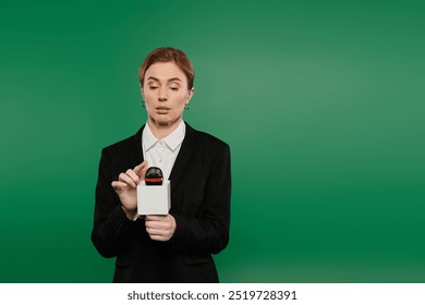 The TV presenter in stylish black attire engages with an audience while standing against a bright green background. - Powered by Shutterstock