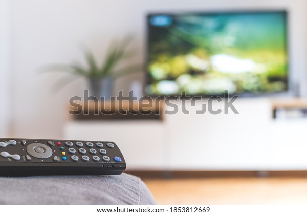TV remote control in the foreground, tv in the\
blurry background.\
Streaming.