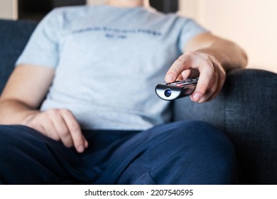 Tv Remote In Hand. Watching Stream Service In Television Sitting On Sofa. Movie Night. Man Streaming Series, Film Or News Online. Change Channel Or Turn On Entertainment Technology. Lazy Couch Potato.