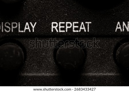 Tv repeat icon and button close up of a old dusty black Television remote controller