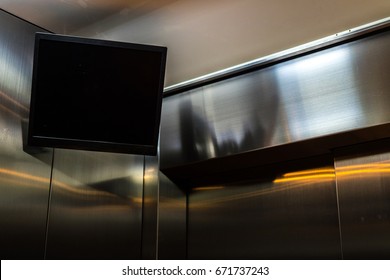 TV Screen Hanging In The Corner Of The Elevator Interior.