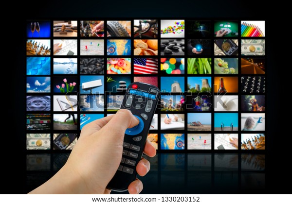 TV screen with lot of pictures and hands of man with\
remote control .