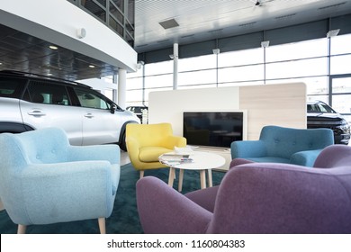 TV Screen, Round Table And Colorful Armchairs For The Customers Of An Elegant Car Dealership