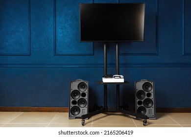 Tv set on metal stand against dark blue wall