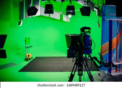 TV Studio recording show.Reportage shooting.TV NEWS program studio with video camera lens and lights.Positioned stage big professional broadcasting camera with headphones.Green key studio