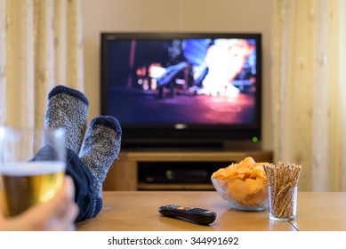 TV, Television Watching (action Movie, Bombing Scene) With Feet On The Table And Snacks - Stock Photo