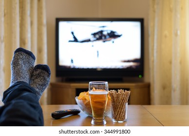 TV, Television Watching (helicopter, War Movie) With Feet On The Table And Snacks - Stock Photo