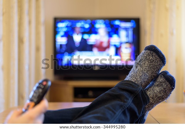 TV, television watching (news) with\
feet on the table and remote in hand - stock\
photo