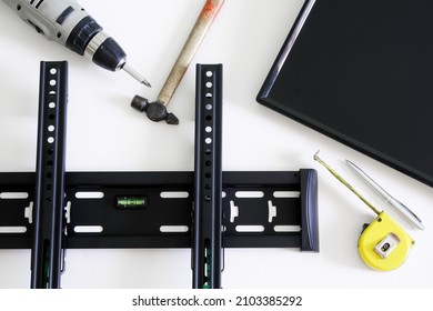 TV wall mount bracket, electric drill, fountain pen, tape measure, hammer and monitor on a white background. The concept of mounting a TV or computer monitor on a wall. Close-up