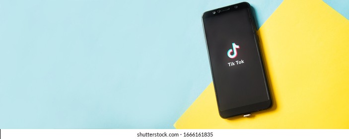 Tver, Russia - February 28, 2020 Tik Tok Logo On Smartphone Screen On Blue And Yellow Background. Tik Tok Icon. Tik Tok Application. Tiktok Social Media Network. Space For Text.