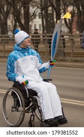 TVER, RUSSIA - MARCH 2, 2014: Torchbearer In A Wheelchair With A Torch On The Paralympic Torch Relay