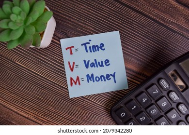 TVM - Time Value Money write on sticky notes isolated on Wooden Table.