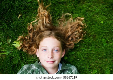 tween aged girl laying on her back in the grass with her hair about her