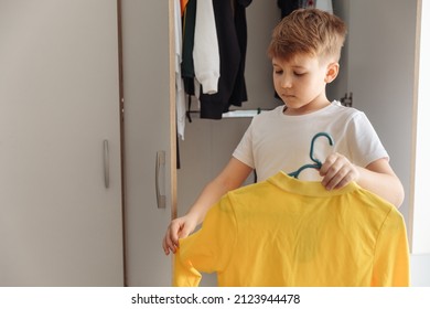 Tween Boy Getting Ready For School In The Morning. Cute Little Boy Open The Closet Wardrobe With Clothes And Thinking What To Wear.