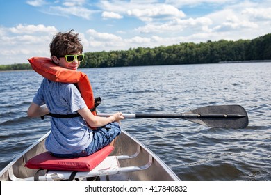 Tween Boy Rowing In A Boat With Oar On A Lake In Summertime