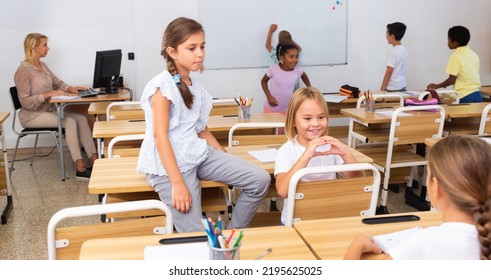 Tween Boys And Girls Friendly Talking In Break Between Lessons Sitting In Classroom