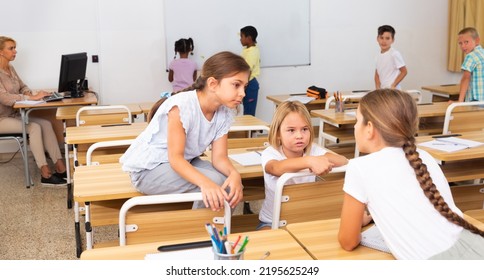 Tween Boys And Girls Friendly Talking In Break Between Lessons Sitting In Classroom