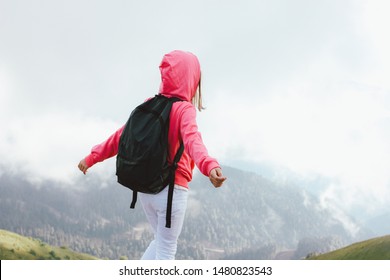 Tween girl with backpack looking on beautiful mountains in the clouds, family travel concept