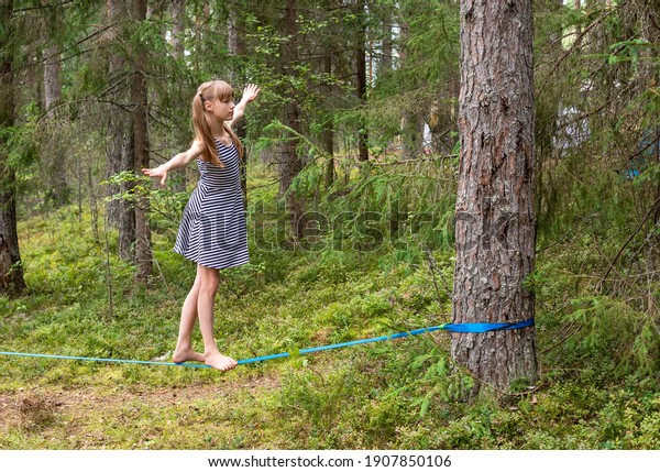 Tween\
girl balancing on slackline during summer\
holidays