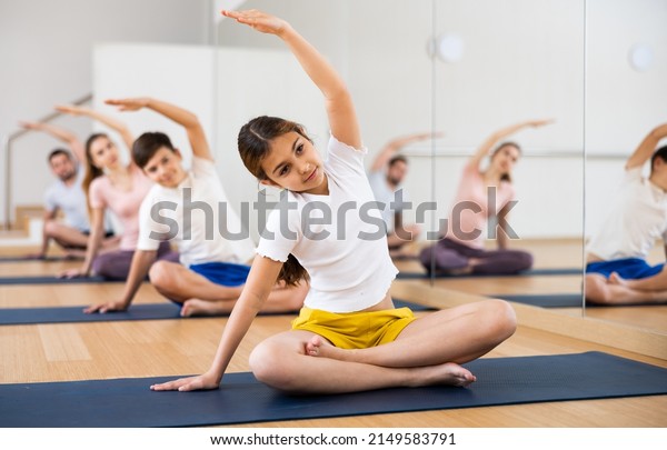 Tween girl exercising\
with brother, mother and father at yoga class, concept of healthy\
family lifestyle