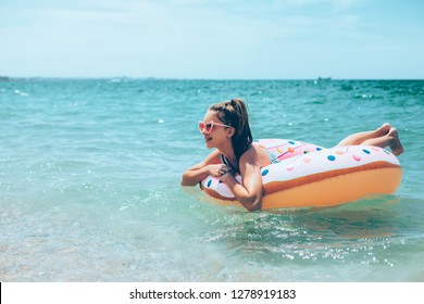 Tween girl relaxing on the inflatable ring on the beach in summer vacations