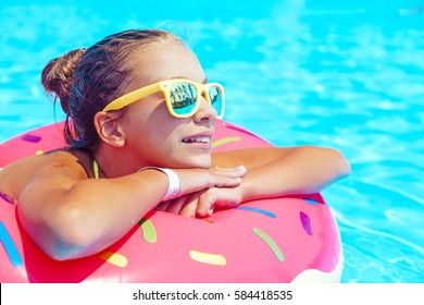 Tween girl relaxing on the inflatable ring in resort pool in Thailand